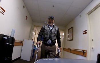 Robot's view of a resident as they walk together down the hallway of an eldercare facility.